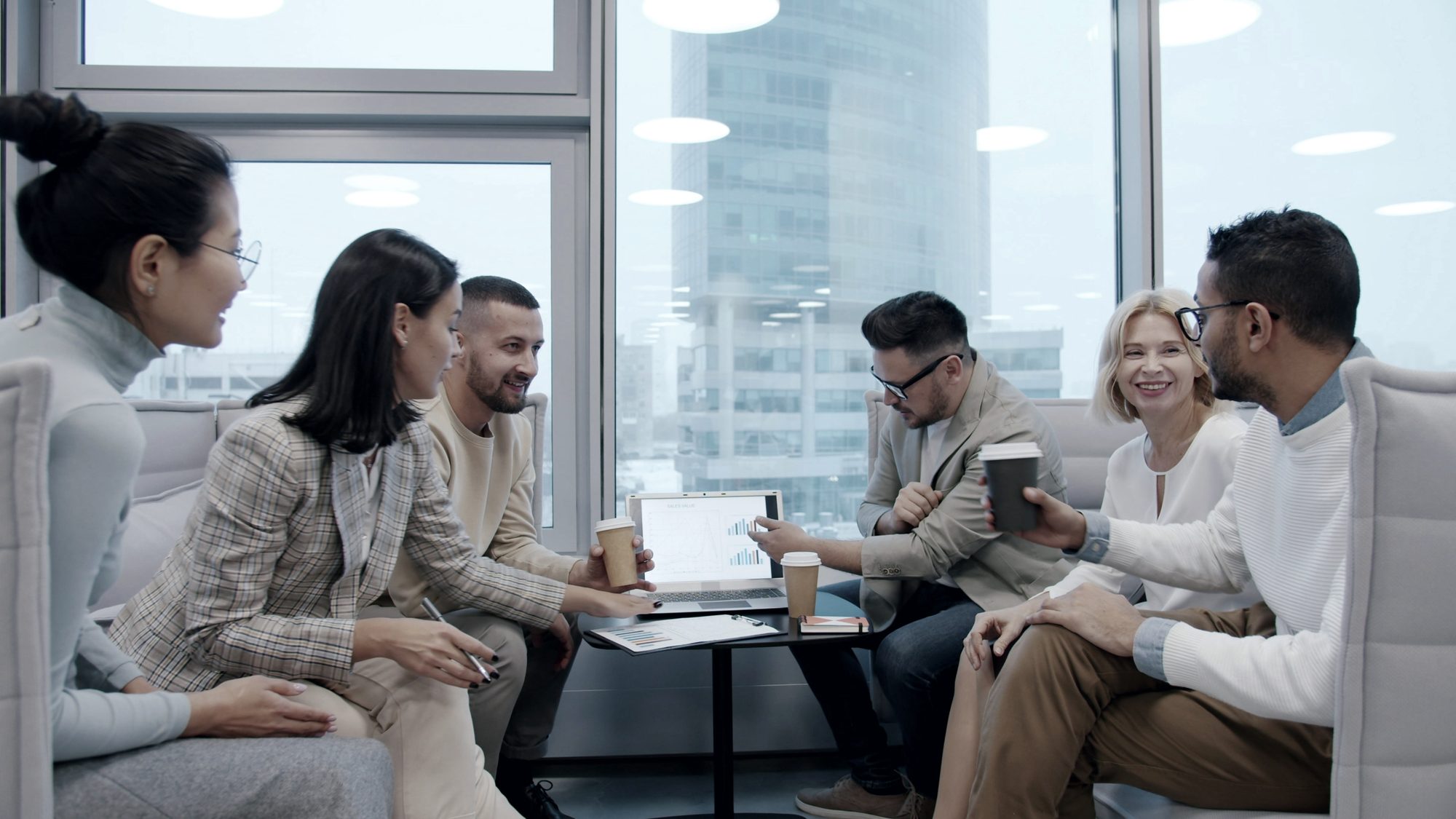 Colleagues discussing work around a laptop in a modern office